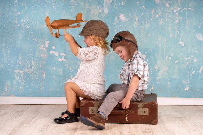 Two children with toy airplane and suitcase