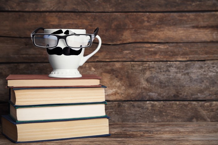 Cup with Moustache and Glasses on Books