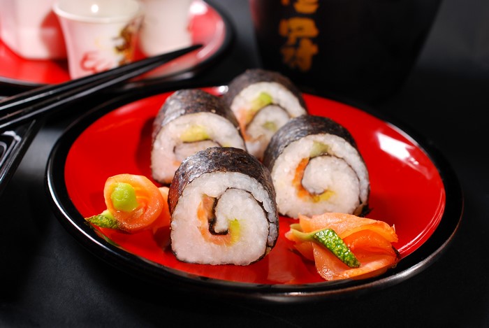 Sushi on a red plate with chopsticks