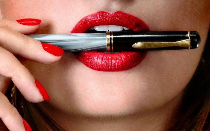 Woman with red lipstick and nails holding a pen