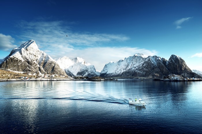 Motorboat on a lake with snow-capped mountains in Lofoten, Norway