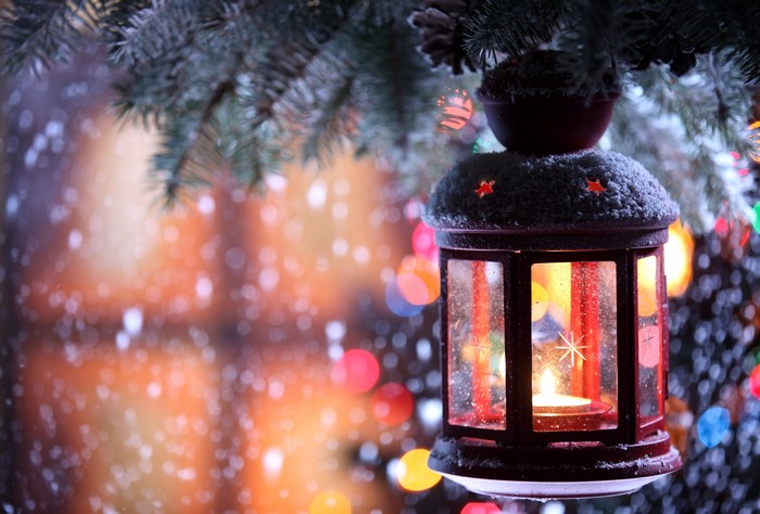 Christmas lantern with candle on a snowy branch