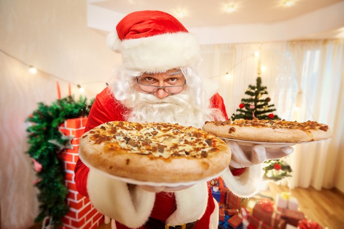 Santa Claus holding two pizzas