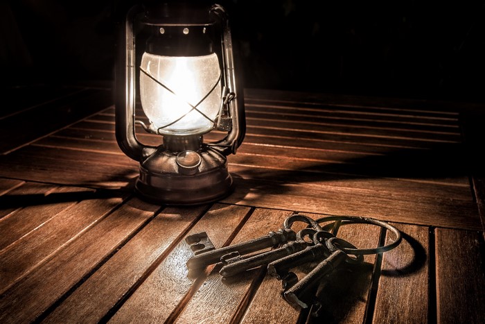 Kerosene lamp and old keys on wooden table