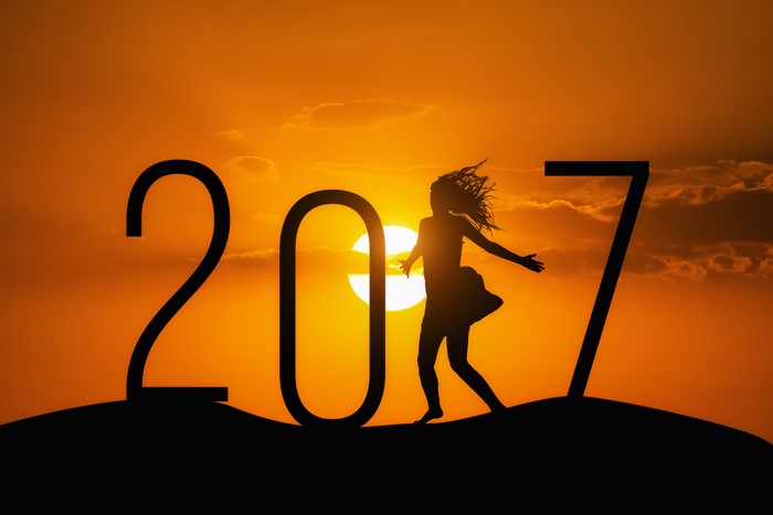 Silhouette of a woman dancing in front of the sun with the year 2017