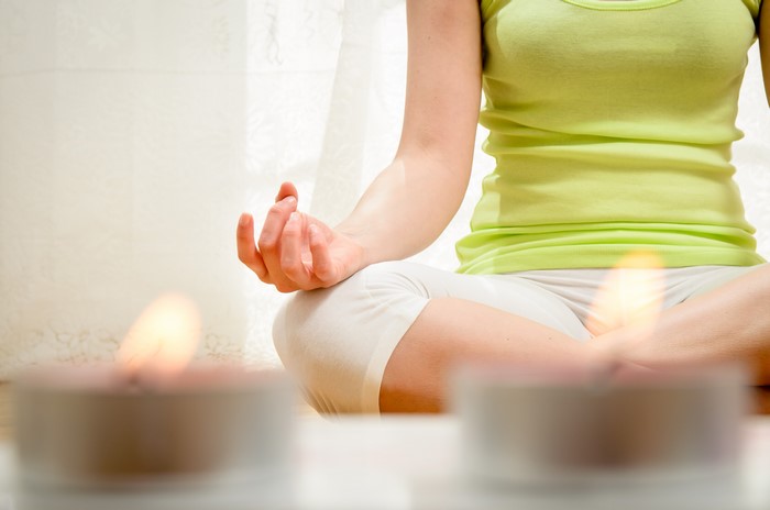 Woman meditating in lotus position with candles