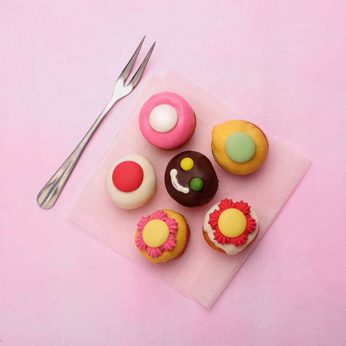 Mini cakes with fork on pink background