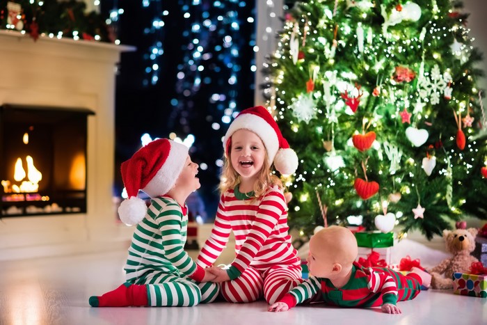 Three Children in Christmas Pajamas by Fireplace and Tree