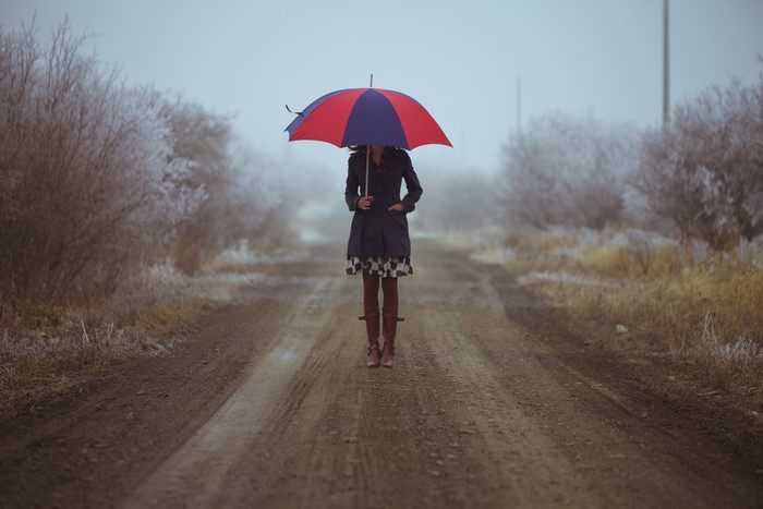 Woman with umbrella on a muddy road