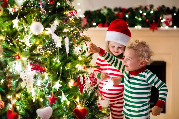 Children decorating a Christmas tree with fairy lights