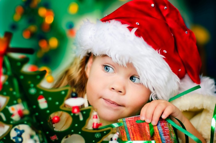 Girl in Santa hat with Christmas tree and gift
