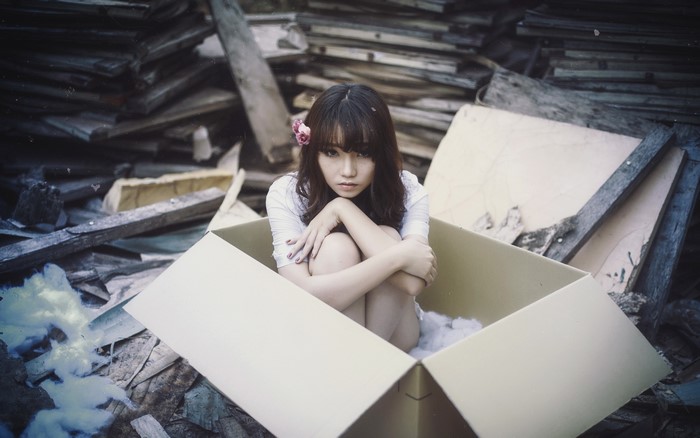 Asian girl sitting in a cardboard box