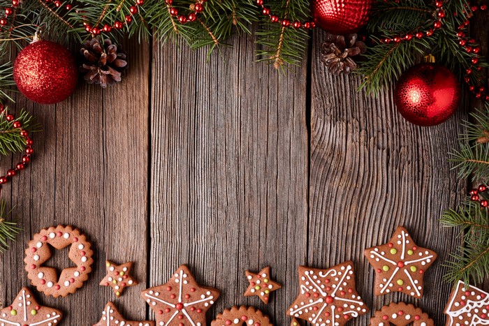 Christmas fir branches, ornaments, pine cones, and cookies on wood