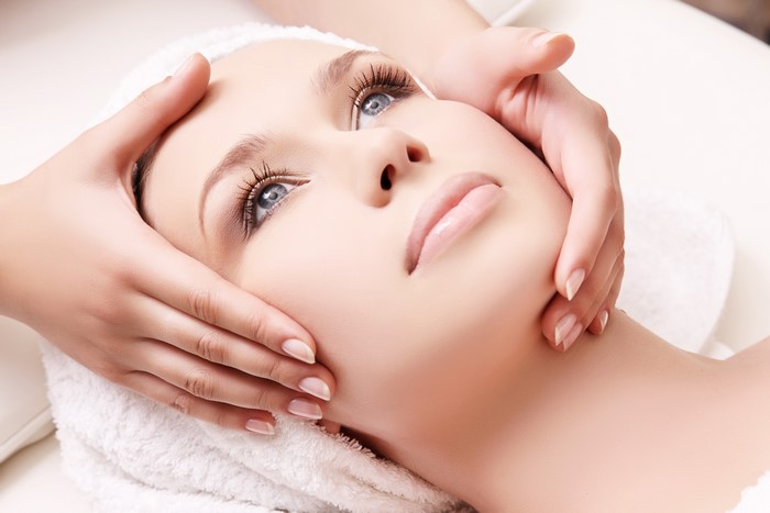 Woman receiving a facial massage with a towel