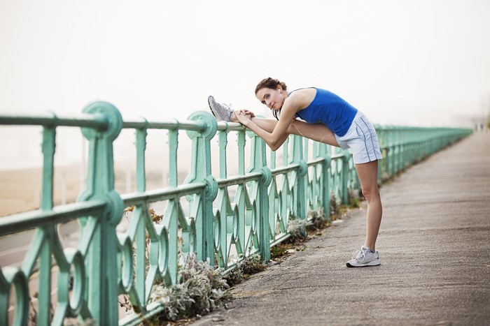 Woman stretching by a fence