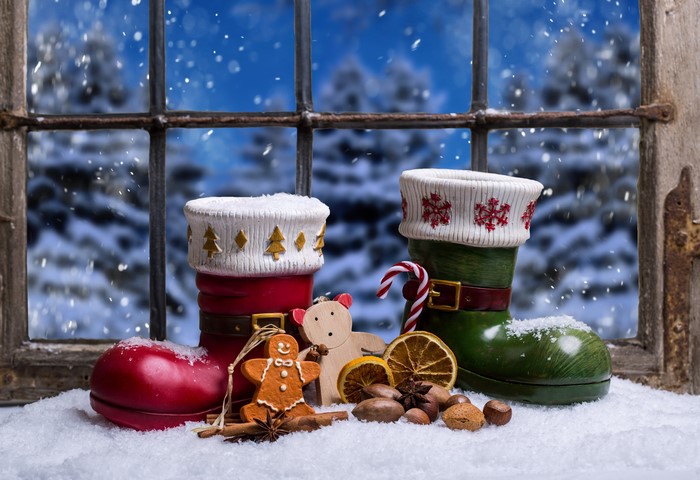 Christmas boots with gingerbread and nuts on a snowy windowsill