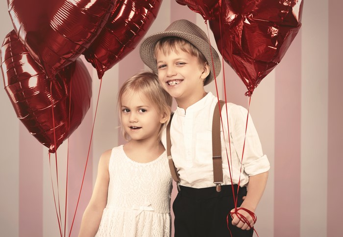Two children with red heart balloons