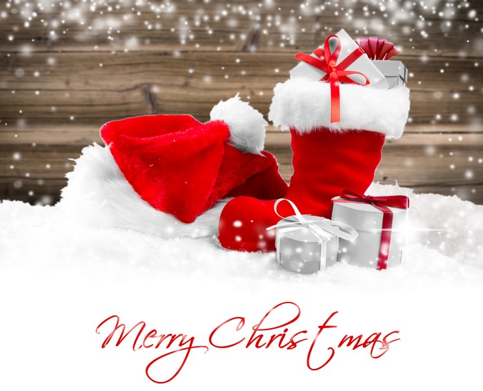 Christmas stocking and Santa hat with gifts in snow