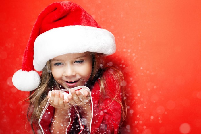 Little girl in Santa hat blowing snow