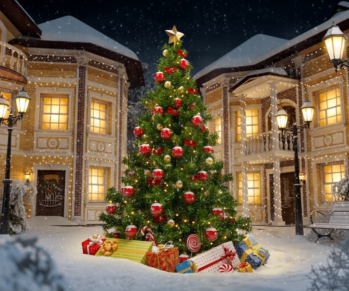 Christmas tree with gifts in a snowy town at night