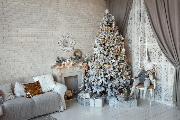 Christmas room with tree, sofa, fireplace, and gifts