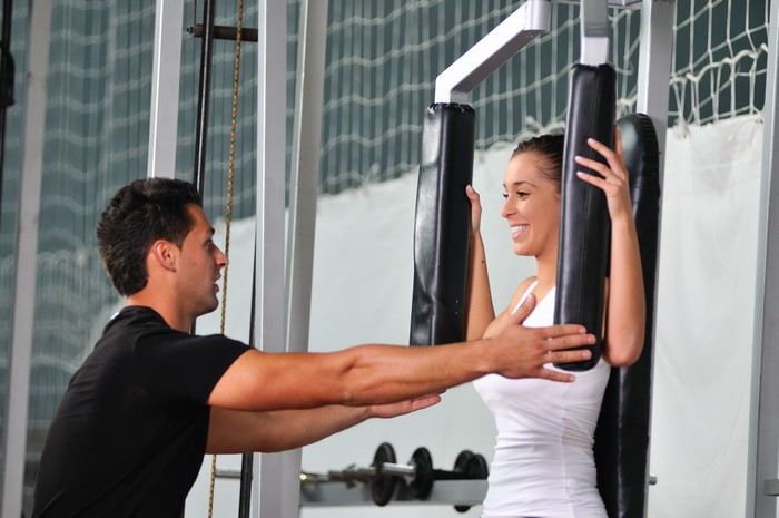 Man coaching woman on fitness machine