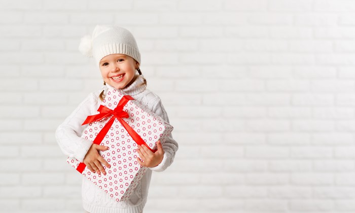Little girl in winter hat holding a gift