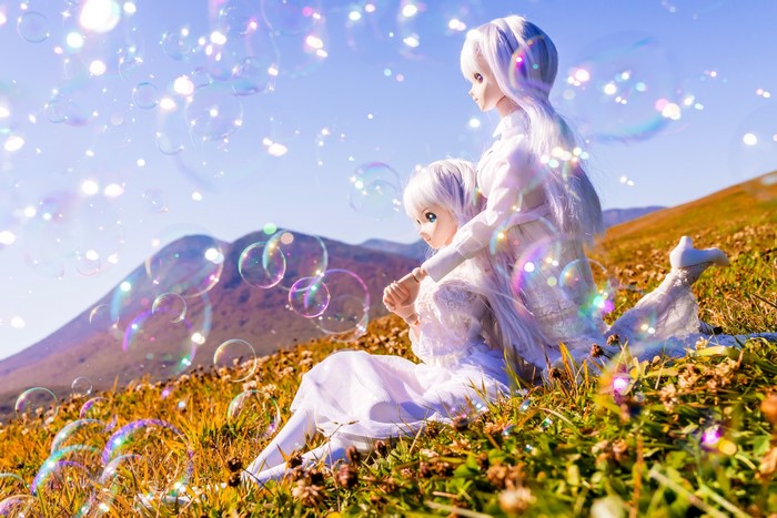 Two dolls with white hair in a field with bubbles