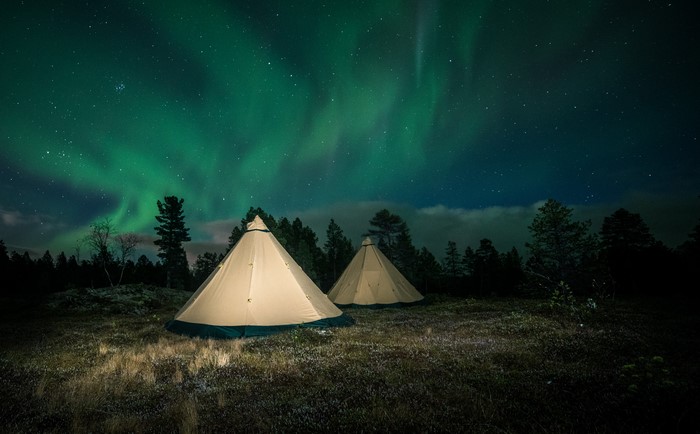 Tents under Aurora Borealis in Lapland, Finland