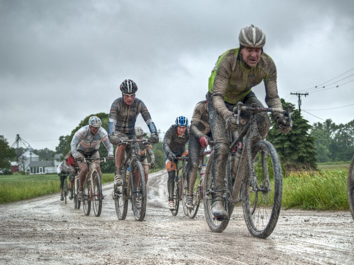 Men racing bicycles on a muddy dirt road