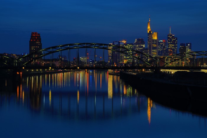 Frankfurt skyline and bridge at night with river reflection