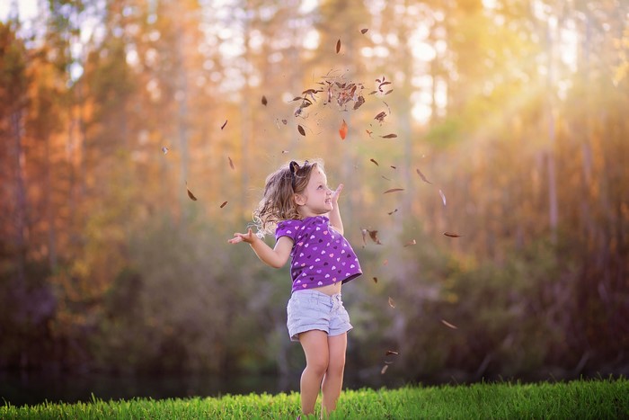 Little girl throwing leaves in autumn