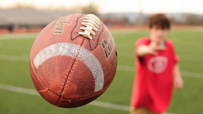 American football in motion with a blurred person in the background