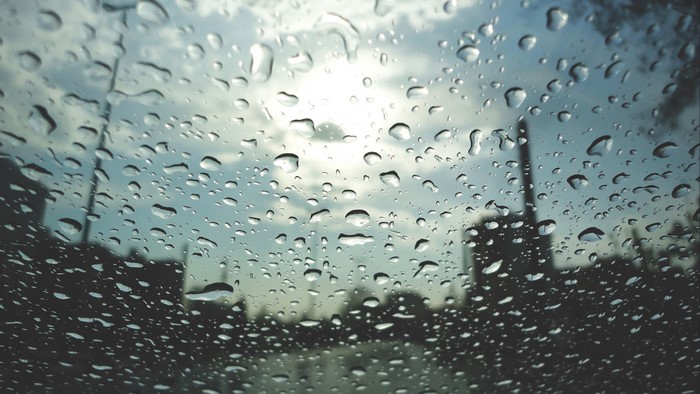 Raindrops on Glass with Cityscape and Sun
