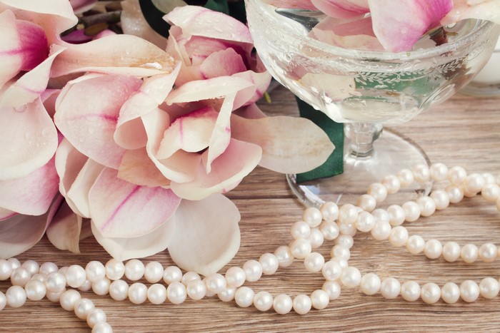 Magnolia petals and pearls with a glass of water
