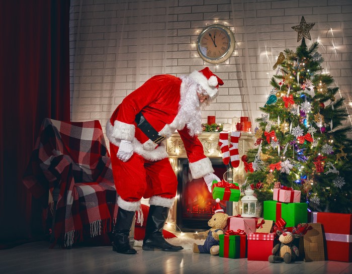Santa Claus placing a gift by the fireplace