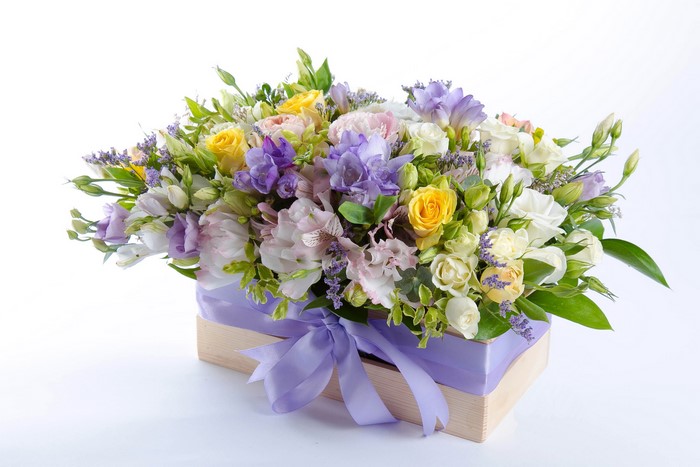 Flower bouquet in a wooden box with a purple ribbon