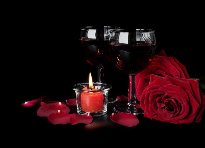 Two glasses of red wine with red roses and candle