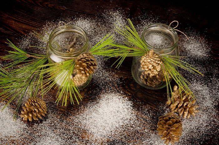 Two jars with pine cones and pine branches on wood