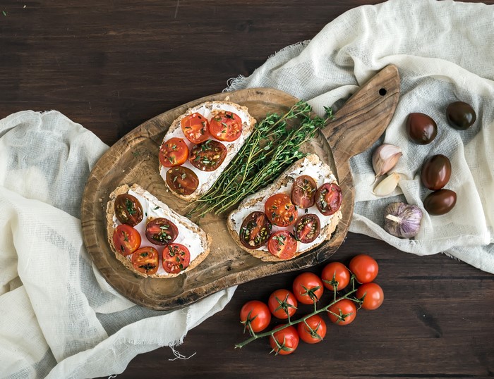 Open-faced sandwiches with tomatoes and cream cheese on a cutting board