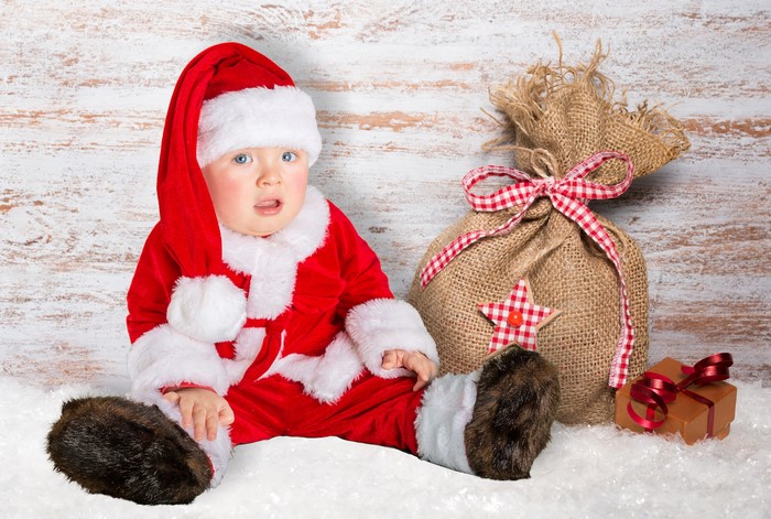 Baby in Santa costume with Christmas gifts