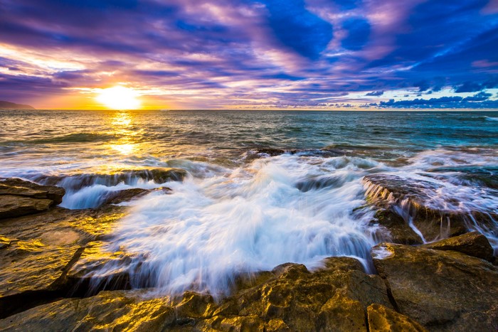 Ocean waves crashing on rocks at sunset in Hawaii