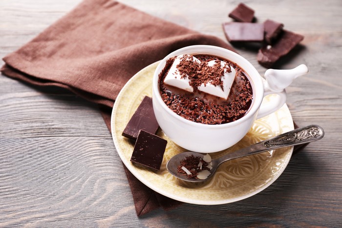 Hot chocolate with marshmallows, chocolate pieces, and a spoon