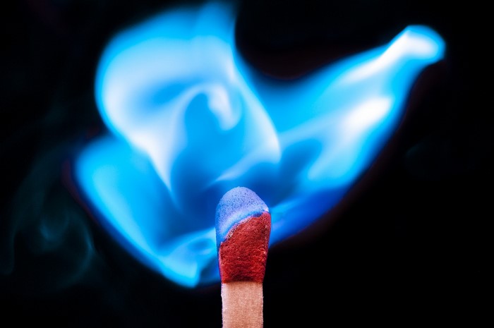 Close-up of a burning match with blue flame