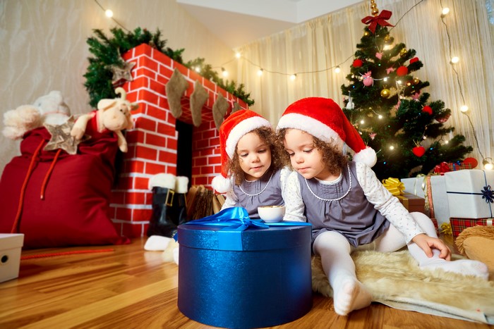 Two little girls in Santa hats with Christmas gifts