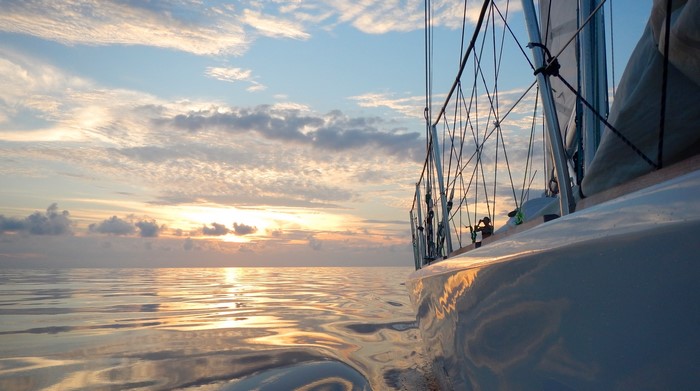 Sailboat on the water at sunset with clouds