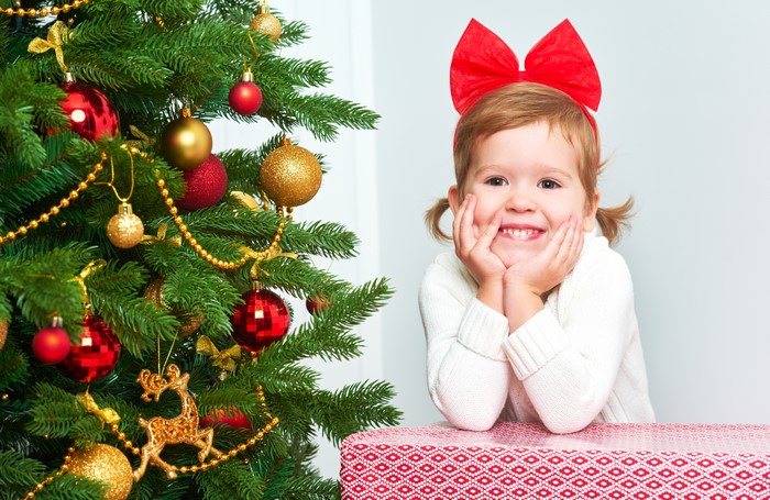 Little girl with red bowknot by Christmas tree