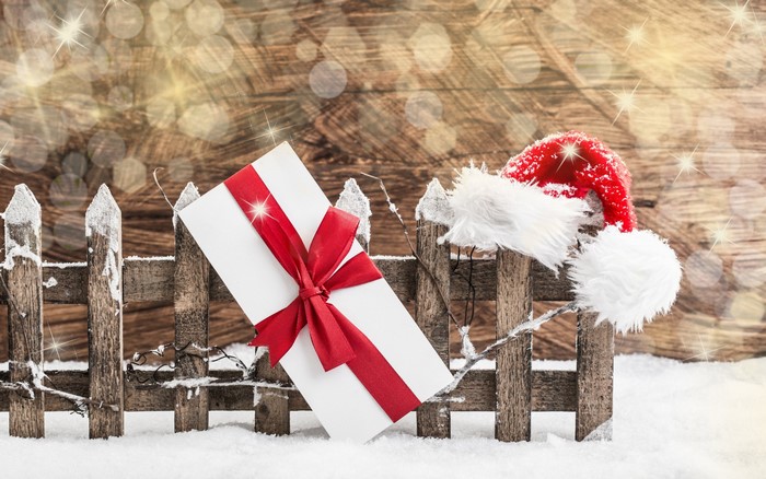 Christmas gift and Santa hat on a snowy fence