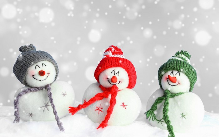 Three snowmen with hats and scarves in the snow