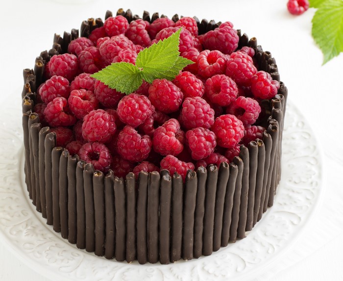 Chocolate cake decorated with raspberries and chocolate sticks